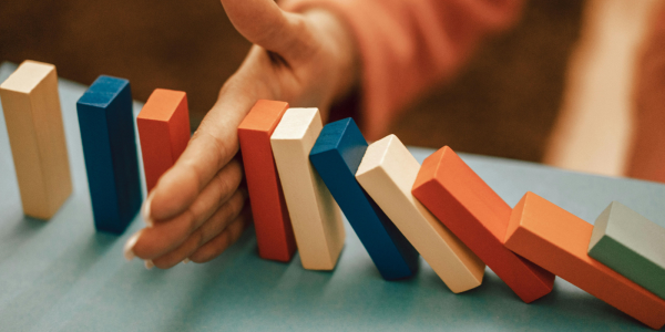 a set of blocks stood on end with a persons hand in the middle, half of the blocks are knocked over, the other half are still stood. a set of blocks stood on end with a persons hand in the middle, half of the blocks are knocked over, the other half are still stood.