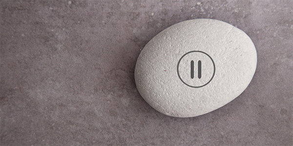 A stone with a pause button stamped onto it.