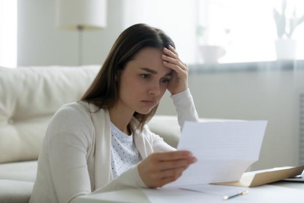 woman holds a document looking distressed