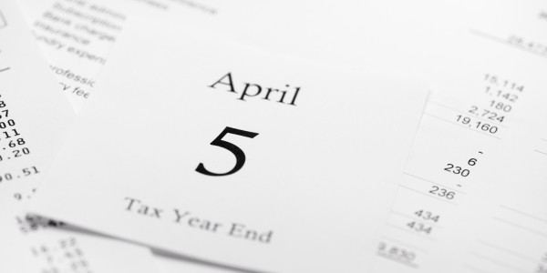 Paperwork spread out, the top piece of paper reads '5 APRIL TAX YEAR END'