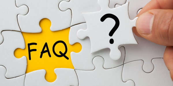 A white jigsaw with one piece left to insert, in the remaining space the letters 'FAQ' can be seen against the yellow surface, the final jigsaw piece has a question mark on it. 