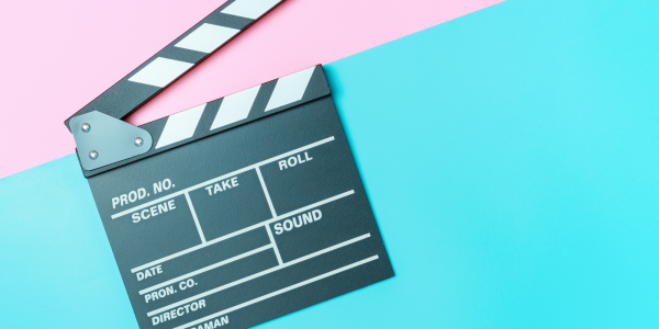Movie set clapboard against a blue and pink background