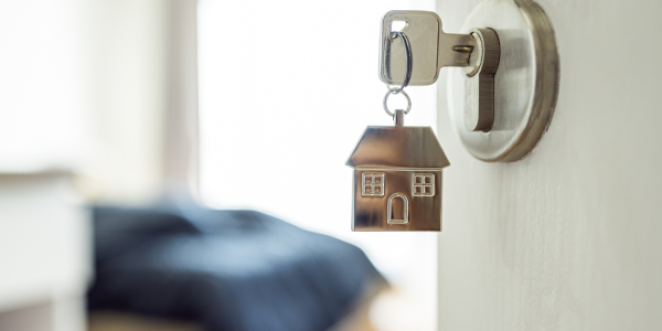 A door with a key in the lock, the keychain is a 2D silver house