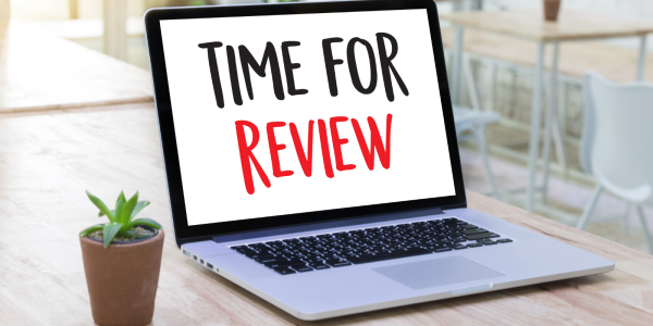 An open laptop with the words 'TIME FOR REVIEW' on the screen