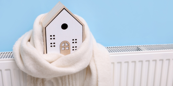A wooden house wrapped in a cream coloured scarf on a radiator 