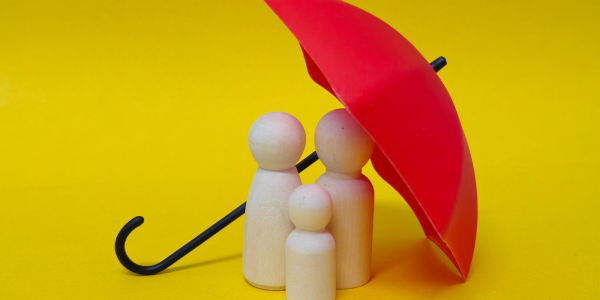 A red umbrella with a wooden family underneath against a yellow background