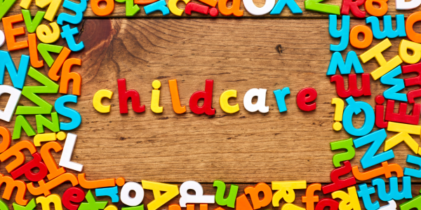 Multi-coloured letters on a wooden background in the centre the letters spell out the word 'CHILDCARE'