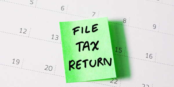 a calendar with a green post it note containing the words 'FILE TAX RETURN' in black ink.