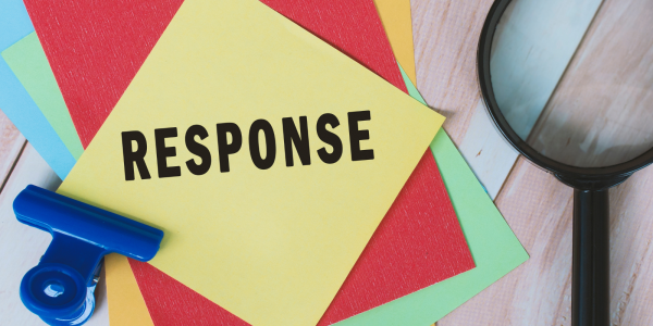 Coloured pieces of paper and desk stationary, the top piece of paper reads the word 'RESPONSE' 
