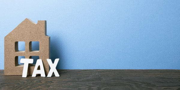 A large wooden house with the wooden letters spelling out the word 'TAX' stood outside