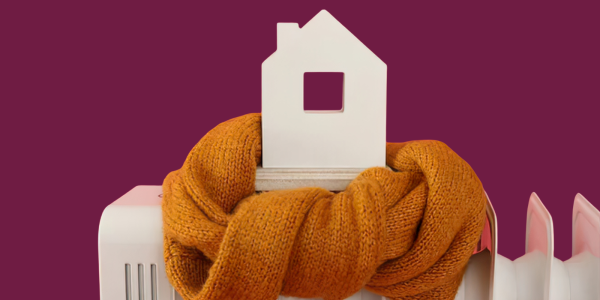 A radiator with a little wooden house on top wrapped in an orange coloured scarf 