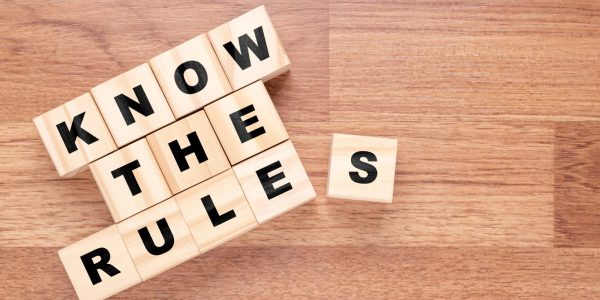 lettered tiles spelling out the words 'KNOW THE RULES' arranged on a wooden floor