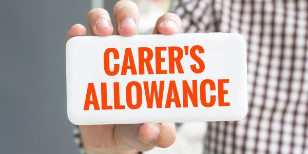 Image of a person hold a sign saying carer's allowance