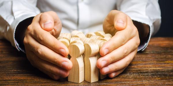 Image of a pair of hands surrounding wooden models of people illustrating job retention
