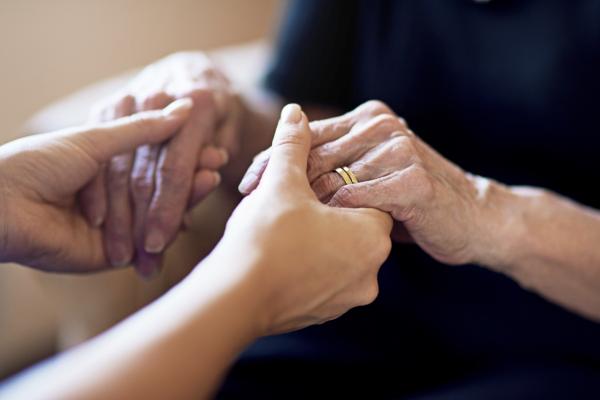 A young person holding hands with an older person. ©istock/PeopleImages