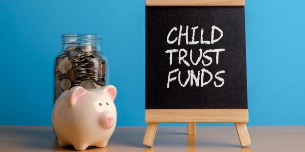 Image of a piggy bank and a board with the words child trust funds written on it