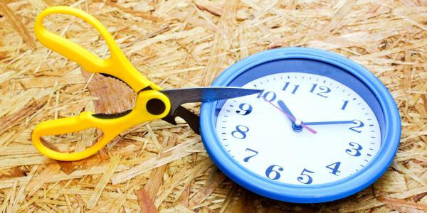 scissors cutting into a clock to signal cut in working hours