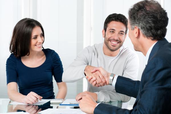 Woman and man, with man shaking hands with man wearing a suit