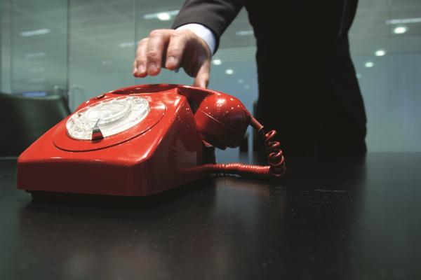 A hand reaching for a red telephone.