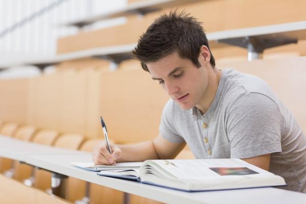 Young man reading / studying and making notes in a lecture hall. ©shutterstock/ESB Professional