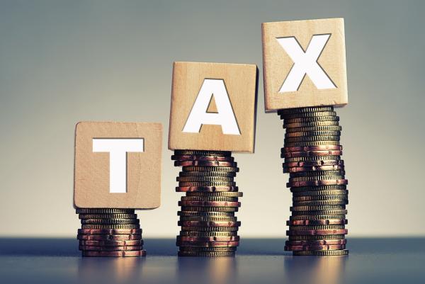 The letters T, A and X sitting on top of a pile of coins.